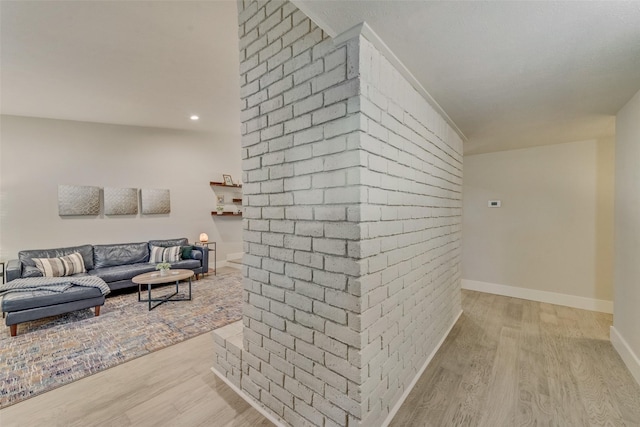 living room with brick wall and light hardwood / wood-style floors