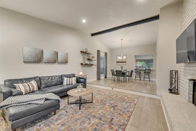 living room with light wood-type flooring, a brick fireplace, an inviting chandelier, and lofted ceiling with beams