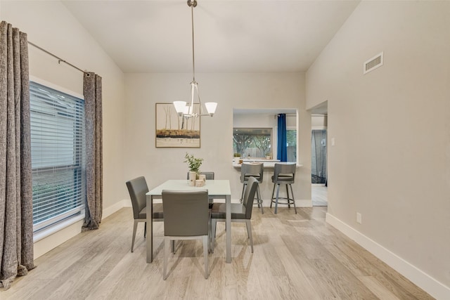 dining room with light hardwood / wood-style flooring and an inviting chandelier