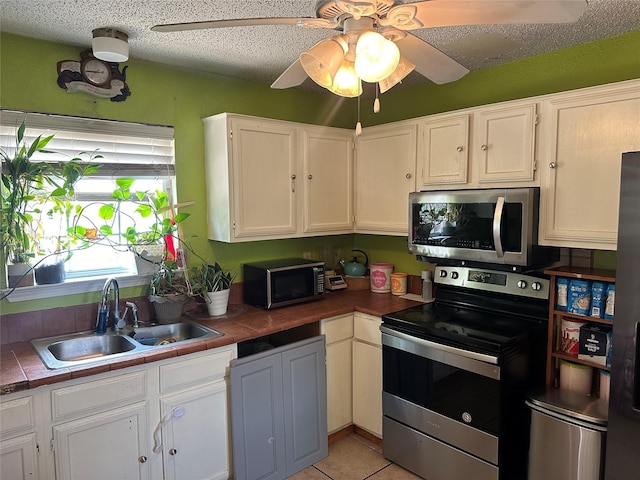 kitchen featuring sink, stainless steel appliances, white cabinets, and tile counters