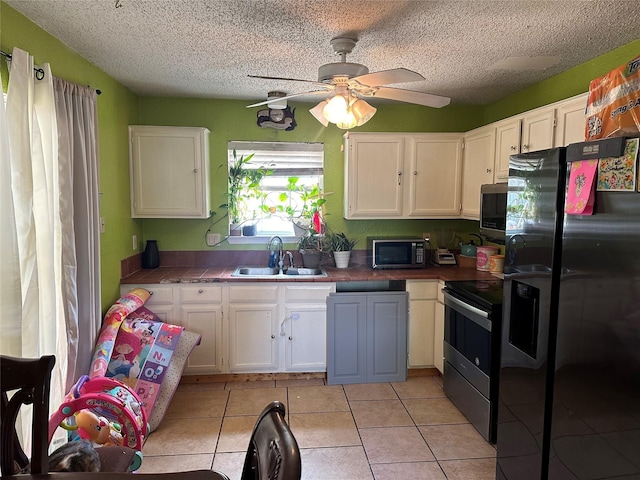 kitchen with black appliances, light tile patterned floors, ceiling fan, sink, and white cabinetry