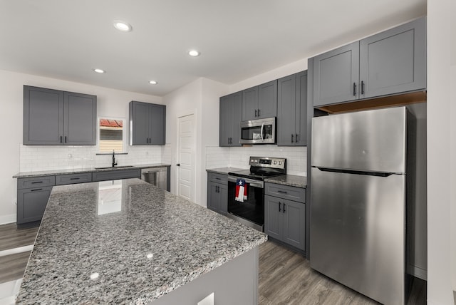 kitchen featuring stainless steel appliances, a center island, sink, and gray cabinets