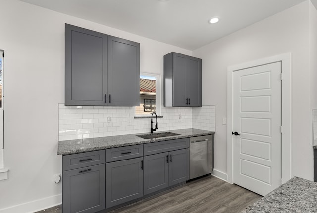 kitchen featuring stone counters, dishwasher, gray cabinetry, and sink