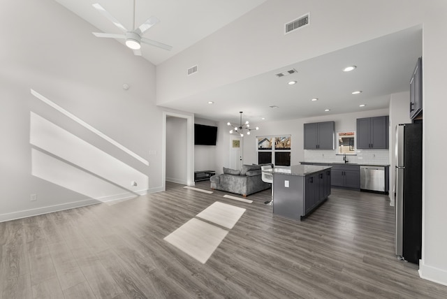 kitchen featuring stainless steel appliances, a center island, ceiling fan with notable chandelier, wood-type flooring, and gray cabinetry