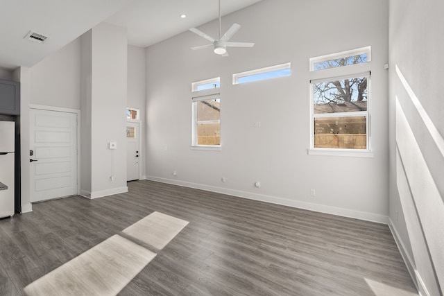 unfurnished living room with a high ceiling, dark wood-type flooring, and ceiling fan