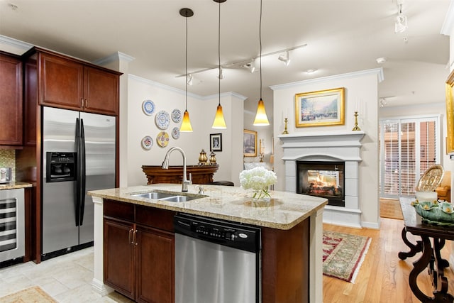 kitchen featuring stainless steel appliances, sink, a multi sided fireplace, hanging light fixtures, and wine cooler