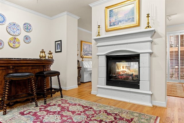 sitting room with light wood-type flooring, ornamental molding, and a multi sided fireplace