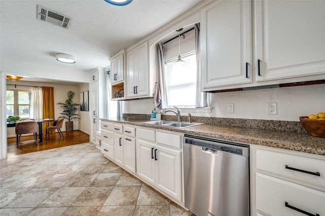 kitchen with white cabinets, hanging light fixtures, stainless steel dishwasher, and sink