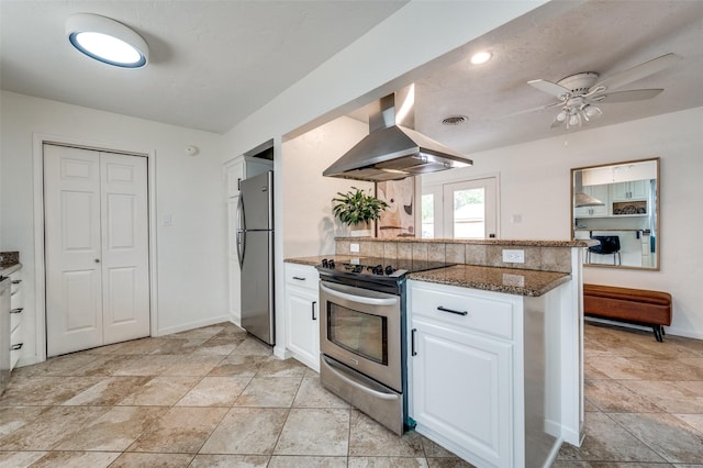 kitchen featuring white cabinets, dark stone countertops, ceiling fan, island range hood, and appliances with stainless steel finishes