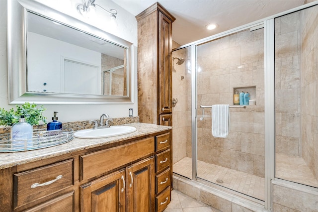 bathroom with tile patterned flooring, walk in shower, and vanity