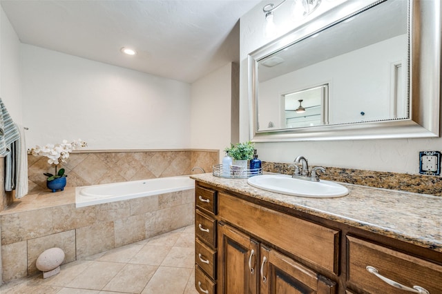 bathroom with ceiling fan, tile patterned flooring, tiled bath, and vanity