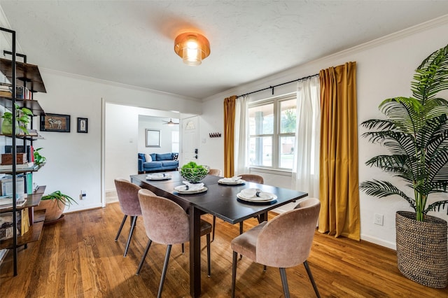 dining area featuring dark wood-type flooring, ceiling fan, and crown molding