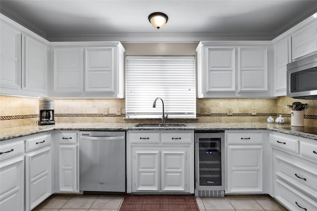 kitchen featuring wine cooler, stainless steel appliances, light tile patterned floors, sink, and white cabinetry