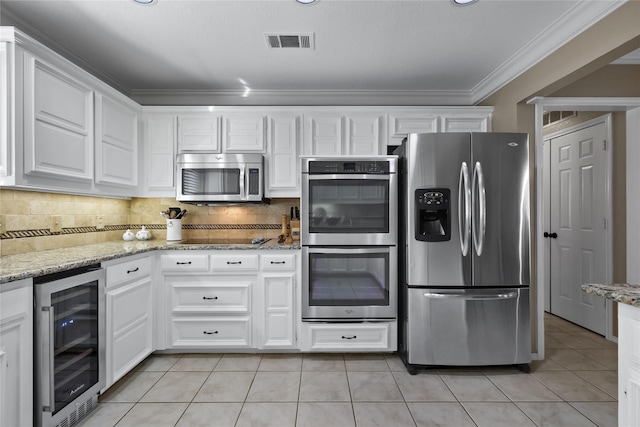 kitchen with light stone counters, beverage cooler, white cabinets, appliances with stainless steel finishes, and ornamental molding