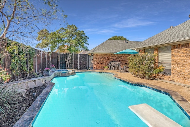 view of pool with a diving board and an in ground hot tub