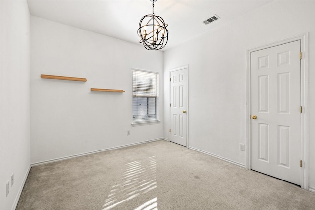 carpeted spare room with an inviting chandelier