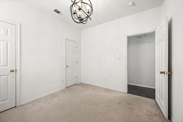 unfurnished bedroom with light colored carpet and a notable chandelier