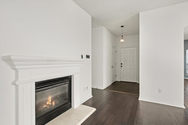 unfurnished living room featuring a tiled fireplace and dark hardwood / wood-style flooring