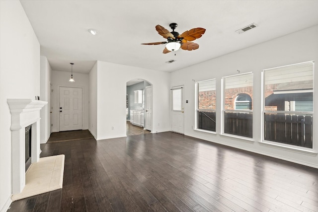 unfurnished living room with a fireplace, ceiling fan, and dark wood-type flooring