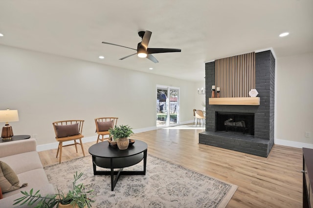 living room with ceiling fan, light wood-type flooring, and a fireplace