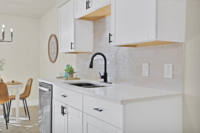 kitchen with dishwasher, a notable chandelier, backsplash, white cabinetry, and sink