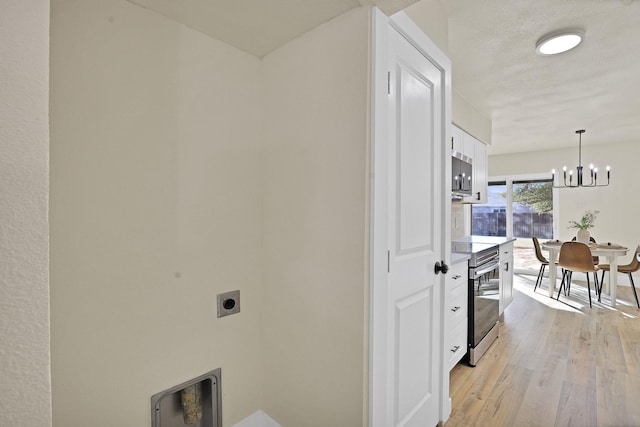 laundry room with a chandelier, light wood-type flooring, a textured ceiling, and hookup for an electric dryer