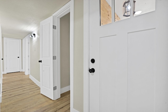 hallway featuring a textured ceiling and light hardwood / wood-style flooring