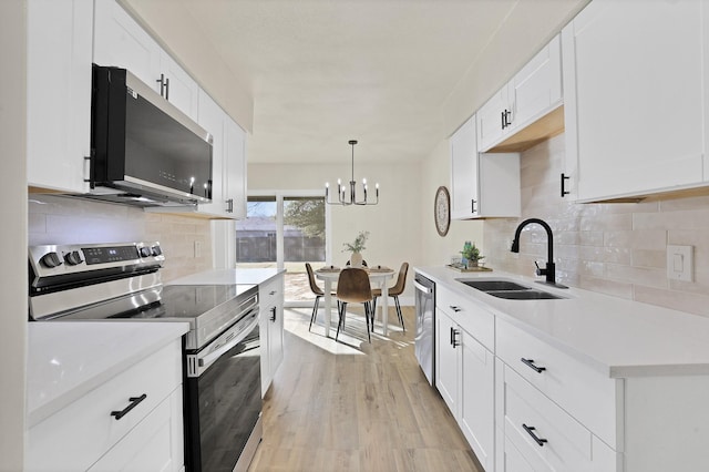 kitchen with decorative light fixtures, a notable chandelier, white cabinetry, appliances with stainless steel finishes, and sink