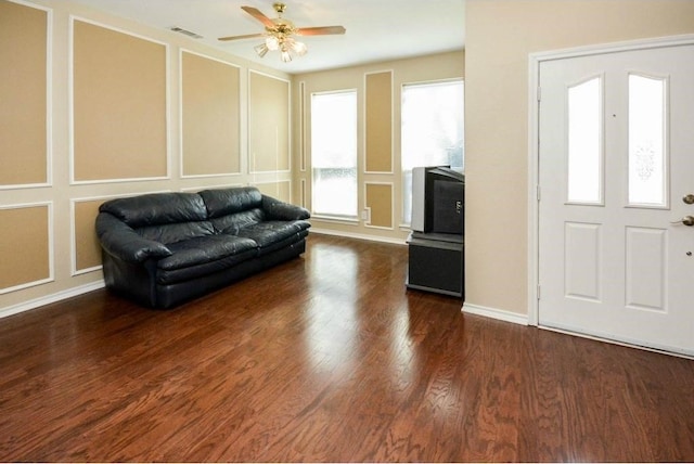 living room with dark wood-type flooring and ceiling fan