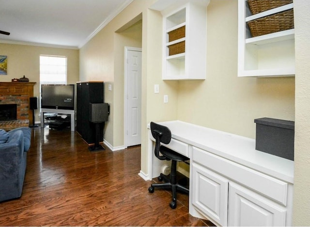 office area featuring built in desk, ornamental molding, dark hardwood / wood-style floors, a fireplace, and built in features