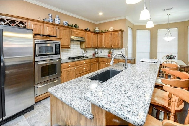 kitchen featuring stainless steel appliances, a breakfast bar area, sink, and light stone countertops