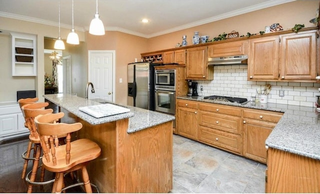 kitchen with decorative light fixtures, stainless steel appliances, light stone countertops, and an island with sink