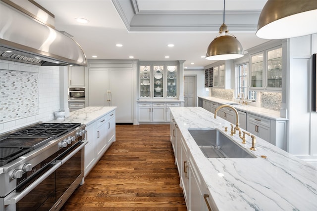 kitchen with island range hood, high quality appliances, decorative backsplash, sink, and white cabinetry