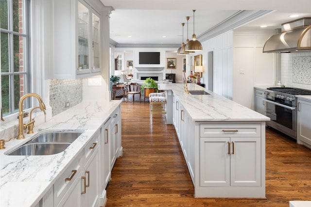 kitchen featuring sink, white cabinets, stainless steel stove, and wall chimney exhaust hood