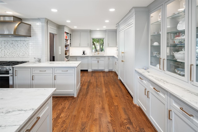 kitchen featuring high end stainless steel range oven, dark hardwood / wood-style flooring, light stone counters, white cabinets, and wall chimney range hood