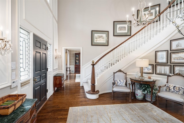 entryway featuring a towering ceiling, an inviting chandelier, and dark hardwood / wood-style floors