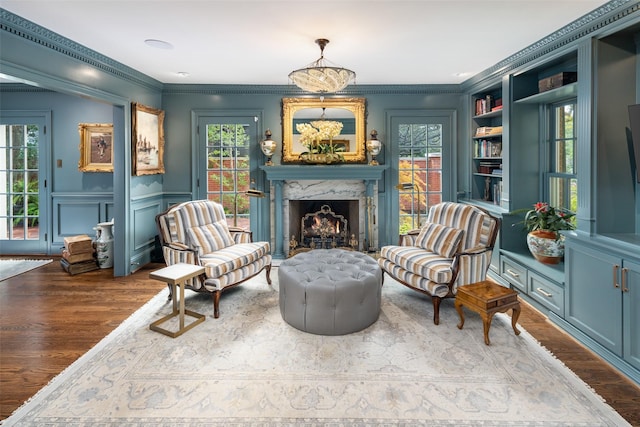 living area with wood-type flooring, a fireplace, ornamental molding, and built in features