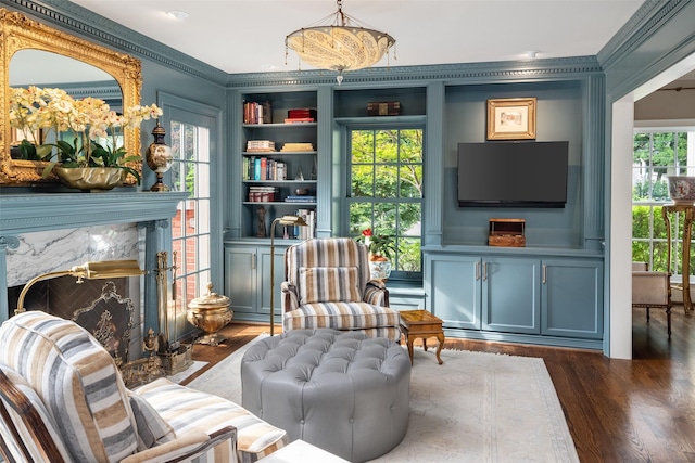 living area with ornamental molding, a healthy amount of sunlight, built in features, and dark wood-type flooring