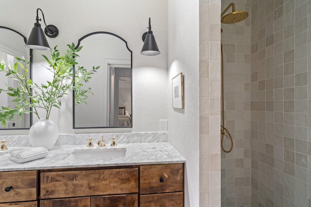 bathroom with a tile shower and vanity