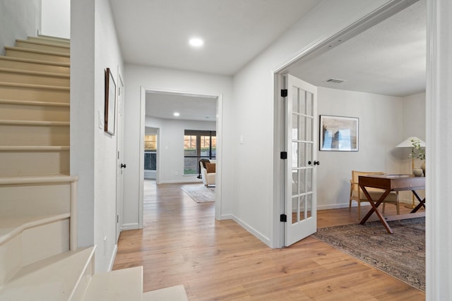 hallway featuring light wood-type flooring and french doors