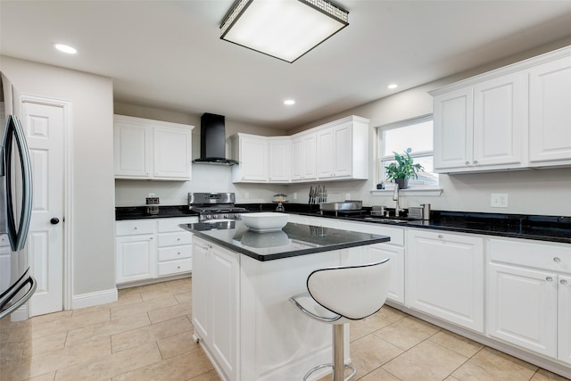 kitchen with sink, white cabinetry, wall chimney exhaust hood, a kitchen island, and appliances with stainless steel finishes