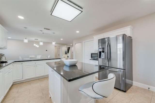 kitchen featuring appliances with stainless steel finishes, pendant lighting, white cabinets, and a kitchen island