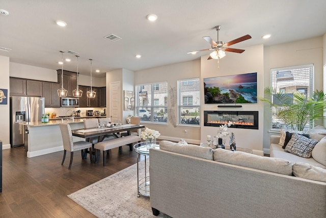 living room with sink, dark wood-type flooring, ceiling fan, and plenty of natural light