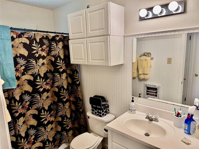 bathroom with heating unit, vanity, and toilet