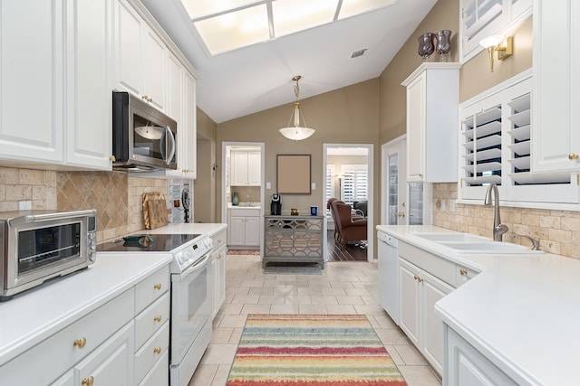 kitchen with white appliances, white cabinets, lofted ceiling, and sink