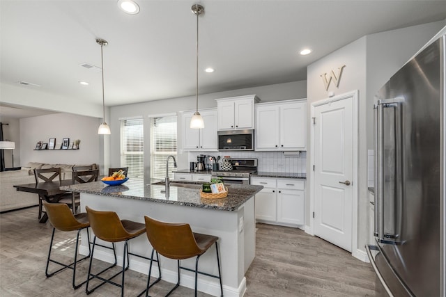 kitchen with stainless steel appliances, white cabinets, and hanging light fixtures