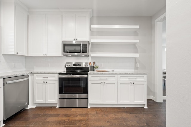 kitchen with appliances with stainless steel finishes, dark wood-type flooring, white cabinetry, and light stone countertops