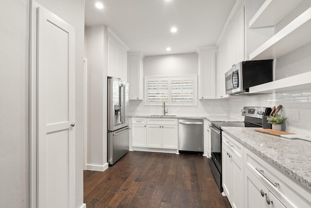 kitchen with sink, appliances with stainless steel finishes, white cabinets, light stone counters, and dark wood-type flooring