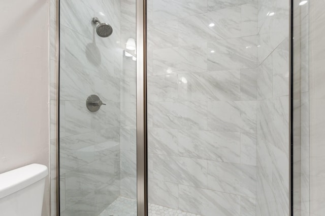 bathroom featuring toilet and a tile shower