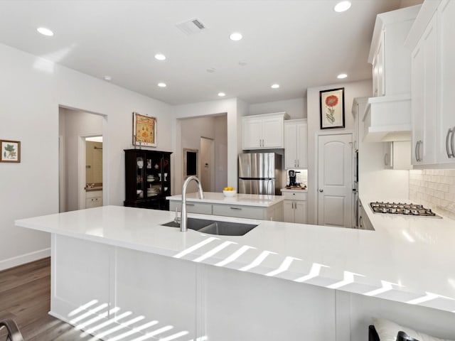 kitchen featuring kitchen peninsula, decorative backsplash, white cabinetry, appliances with stainless steel finishes, and sink